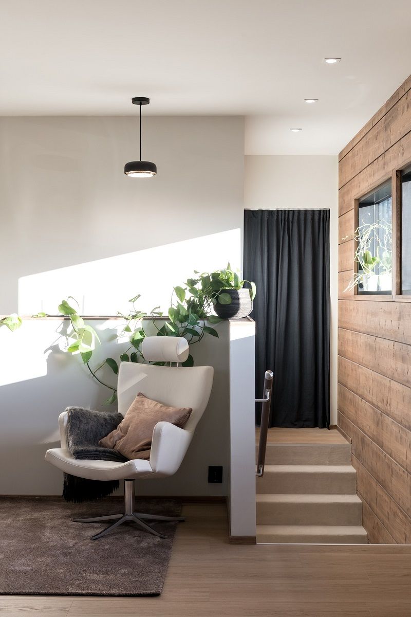 In the corner of the living room with black pendant lighting, and in the corridor with flush-mounted spotlights